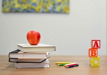 Stack of books, colored pencils and letter blocks sitting on desk