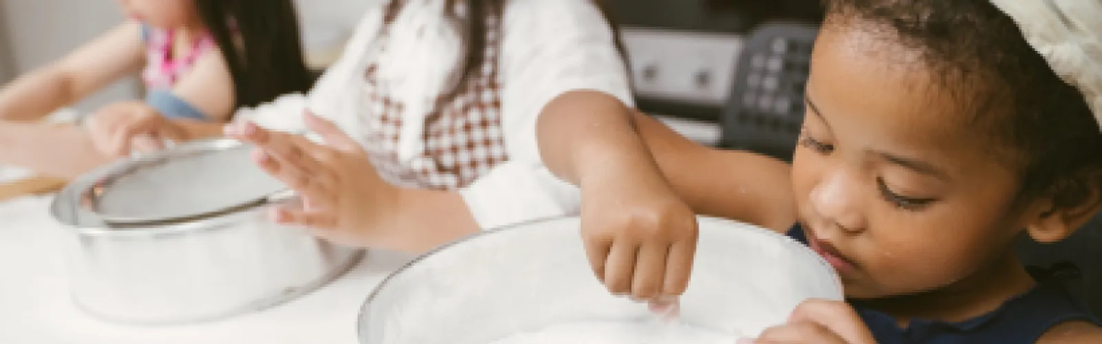 A child mixing flour in a mixing bowl.